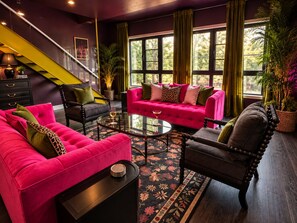 A modern living room with a staircase, a pink sofa set, and a glass coffee table. - Romantic  Couples Getaway • W/Fireplace &Private Patio • Walk Everywhere (Saugatuck)