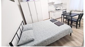 A compact bedroom with a bed, a small kitchenette, and a dining area.