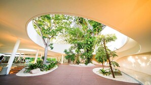 Een binnentuin met een gebogen plafond, omringd door planten en zitgedeeltes.