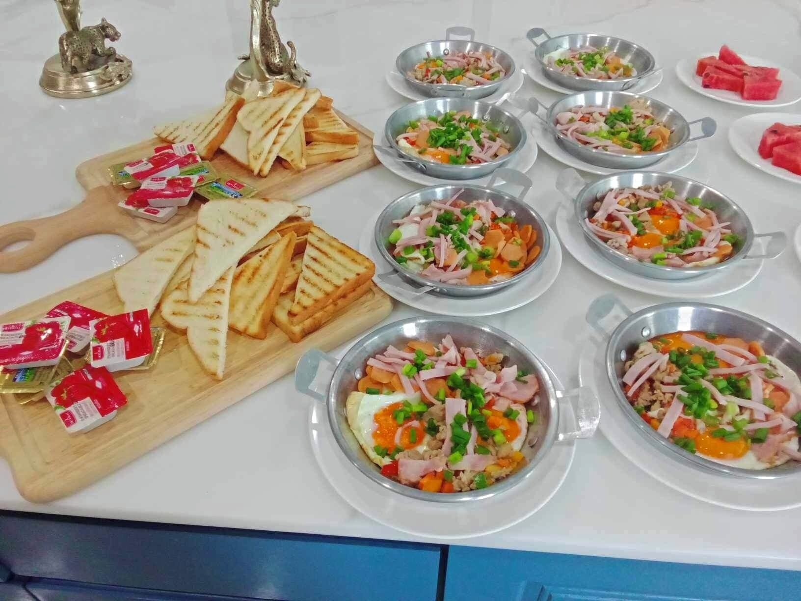 Une table de buffet proposant divers plats, notamment des sandwichs et des salades, disposés sur une table blanche.