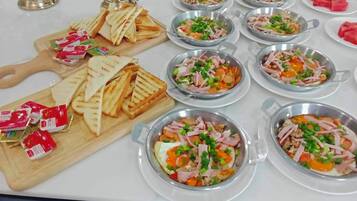 Une table de buffet proposant divers plats, notamment des sandwichs et des salades, disposés sur une table blanche.