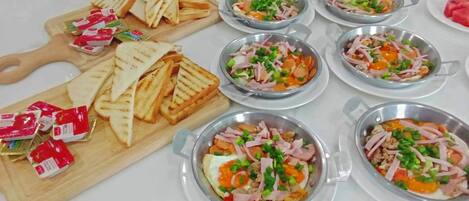 A buffet table with various dishes, including sandwiches and salads, arranged on a white table.