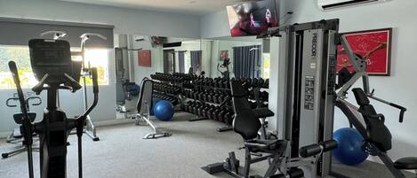 A gym with exercise equipment, a TV, and an air conditioning unit.