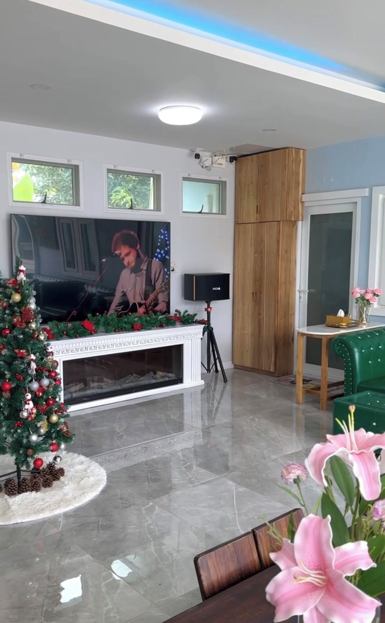 A modern living room with a fireplace, a Christmas tree, and a television.