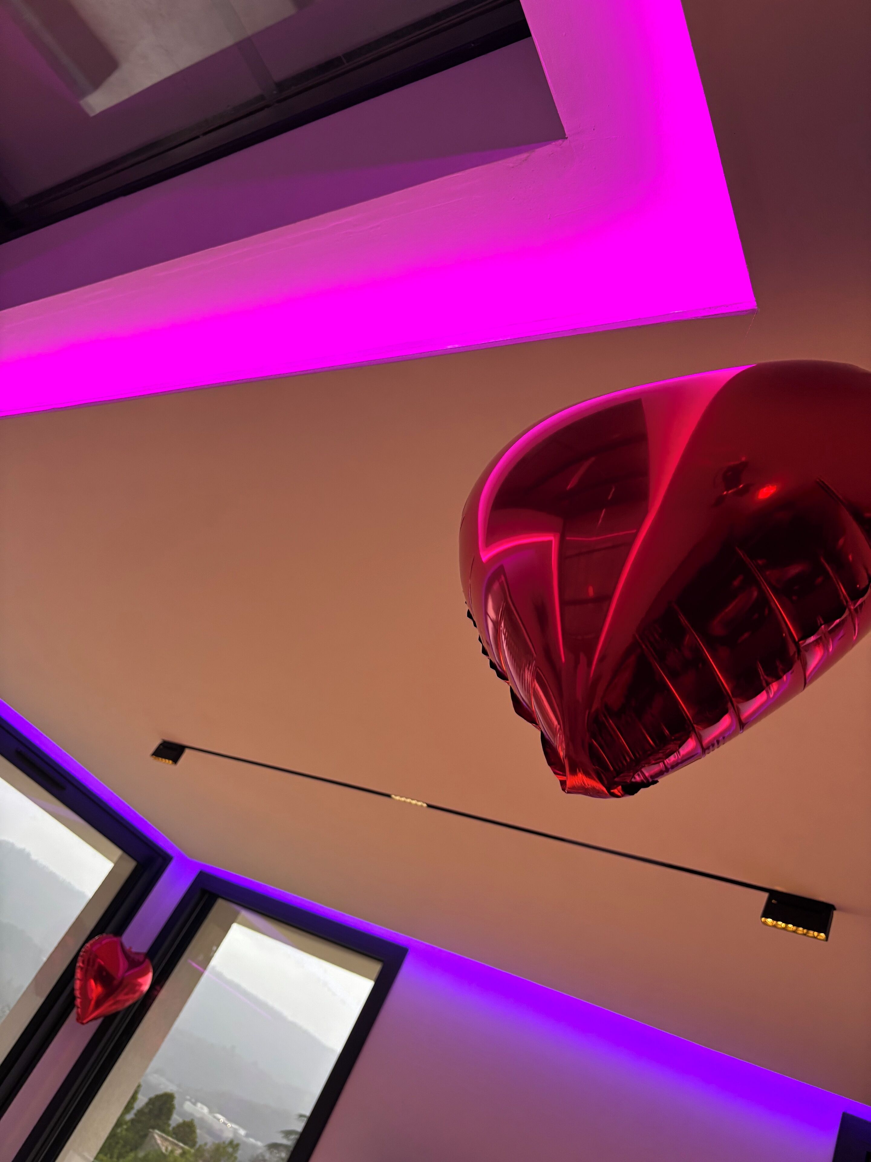 A modern interior with a large window, a red balloon, and purple lighting.