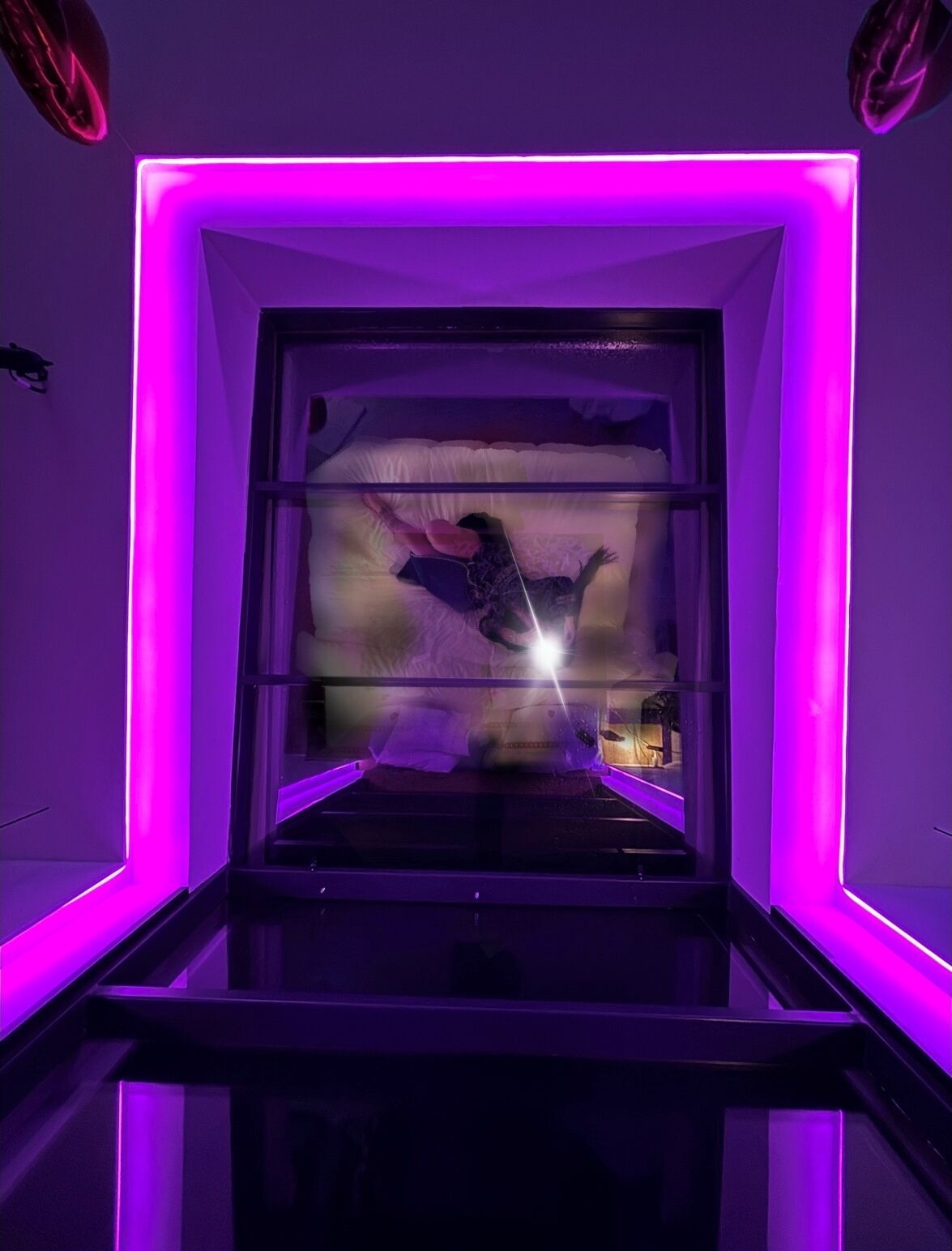 A room with a glass partition and purple lighting.