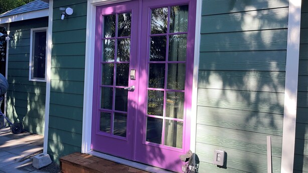 Una casa con una porta viola e rivestimento verde.