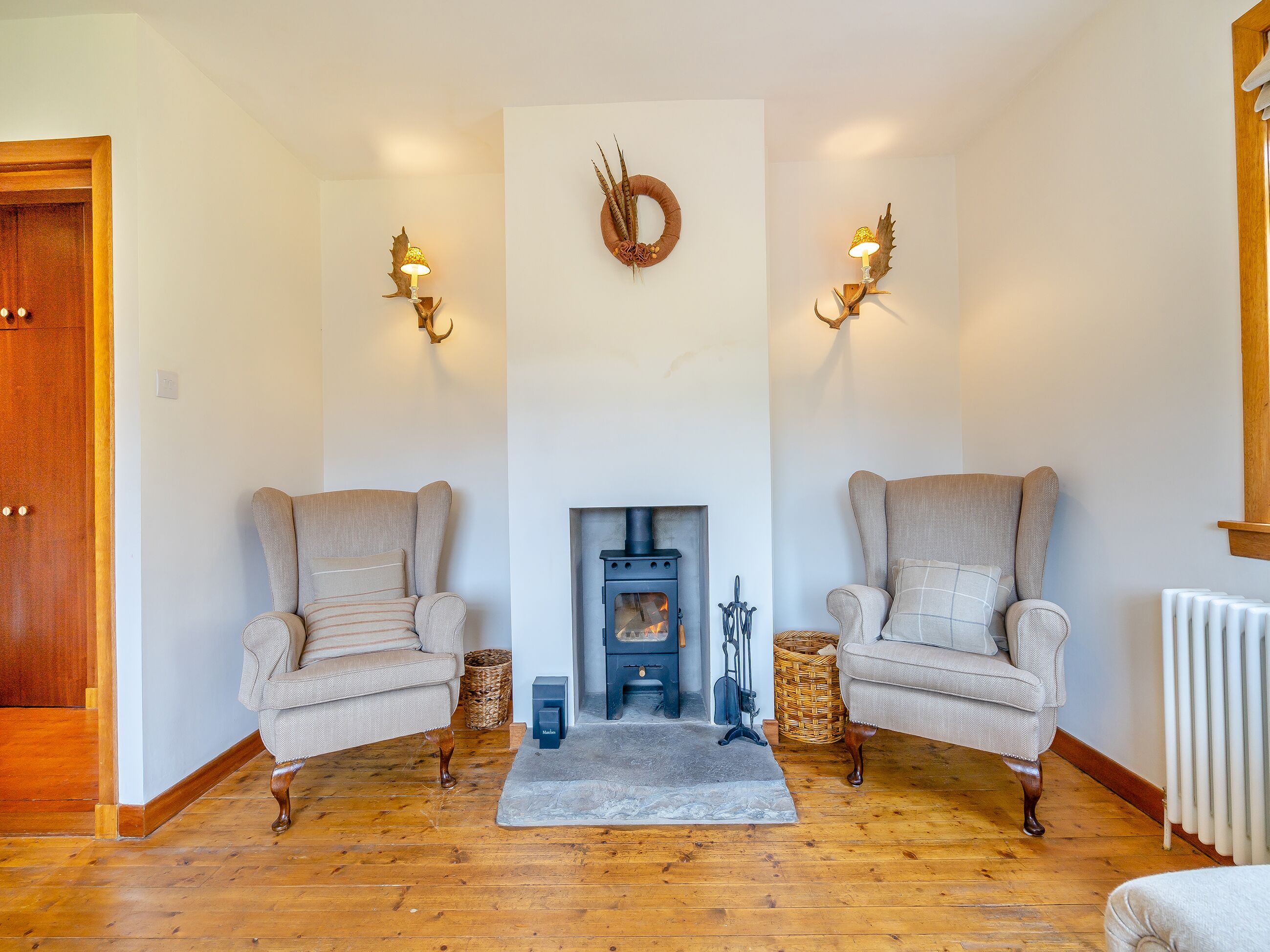 A cozy living room with two armchairs, a fireplace, and decorative wall sconces.