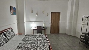 Ein Schlafzimmer mit Bett, Schreibtisch, Stuhl, Tür und Regal.