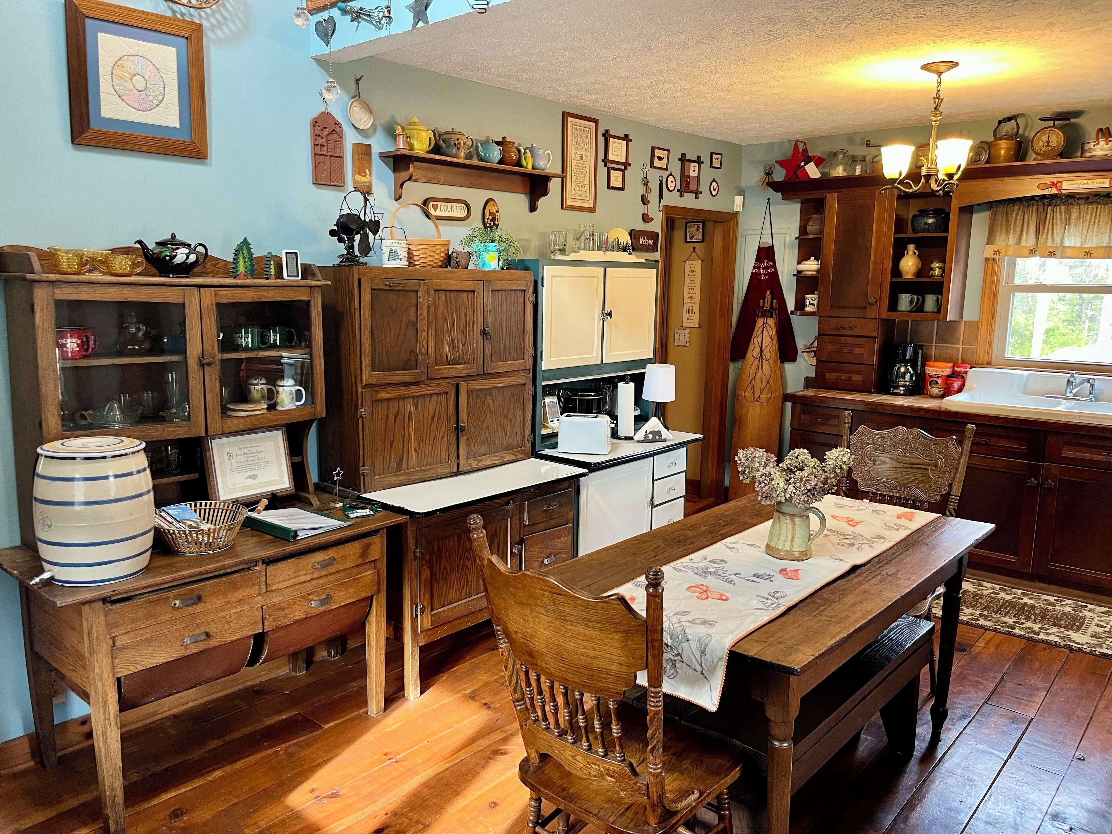 A traditional kitchen with wooden cabinets, a dining table with chairs, and various kitchen utensils and decorations.