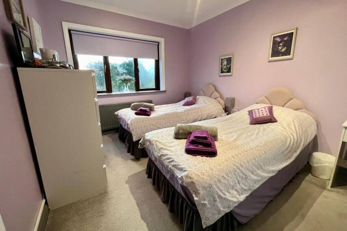 A bedroom with two beds, a window, and a refrigerator.