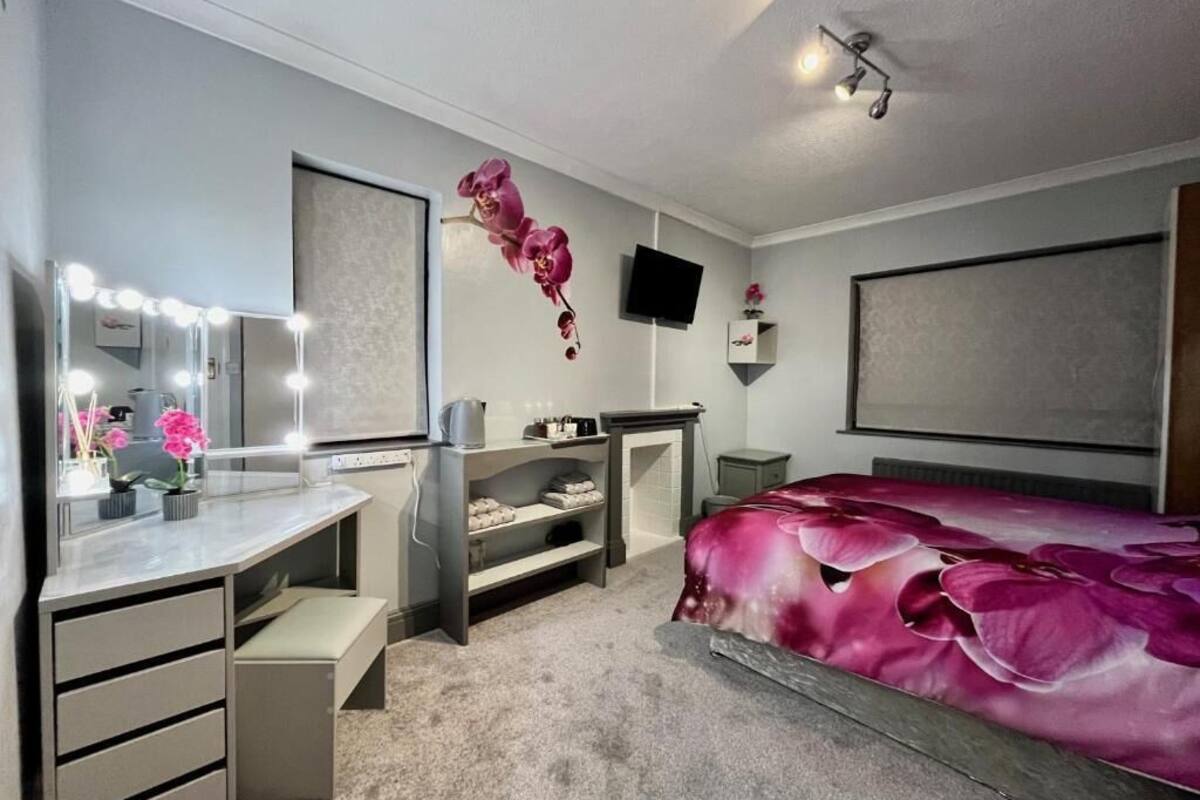A bedroom with a vanity, mirror, and TV.