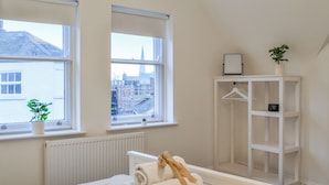 A bedroom with a bed, two windows, a radiator, a white wardrobe, and a small plant on the windowsill. - The location for exploring York is fantastic. (York)