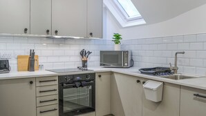 A modern kitchen with white cabinets, a built-in oven, a microwave, and a skylight. - The location for exploring York is fantastic. (York)