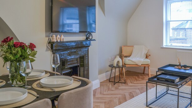 A dining area with a fireplace, a television mounted above it, and a window with blinds. - The location for exploring York is fantastic. (York)