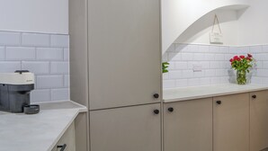 A modern kitchen with white cabinets, a built-in espresso machine, and a vase with red flowers on the counter. - The location for exploring York is fantastic. (York)