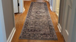 Un couloir avec un tapis à motifs, un plancher en bois et des portes blanches.