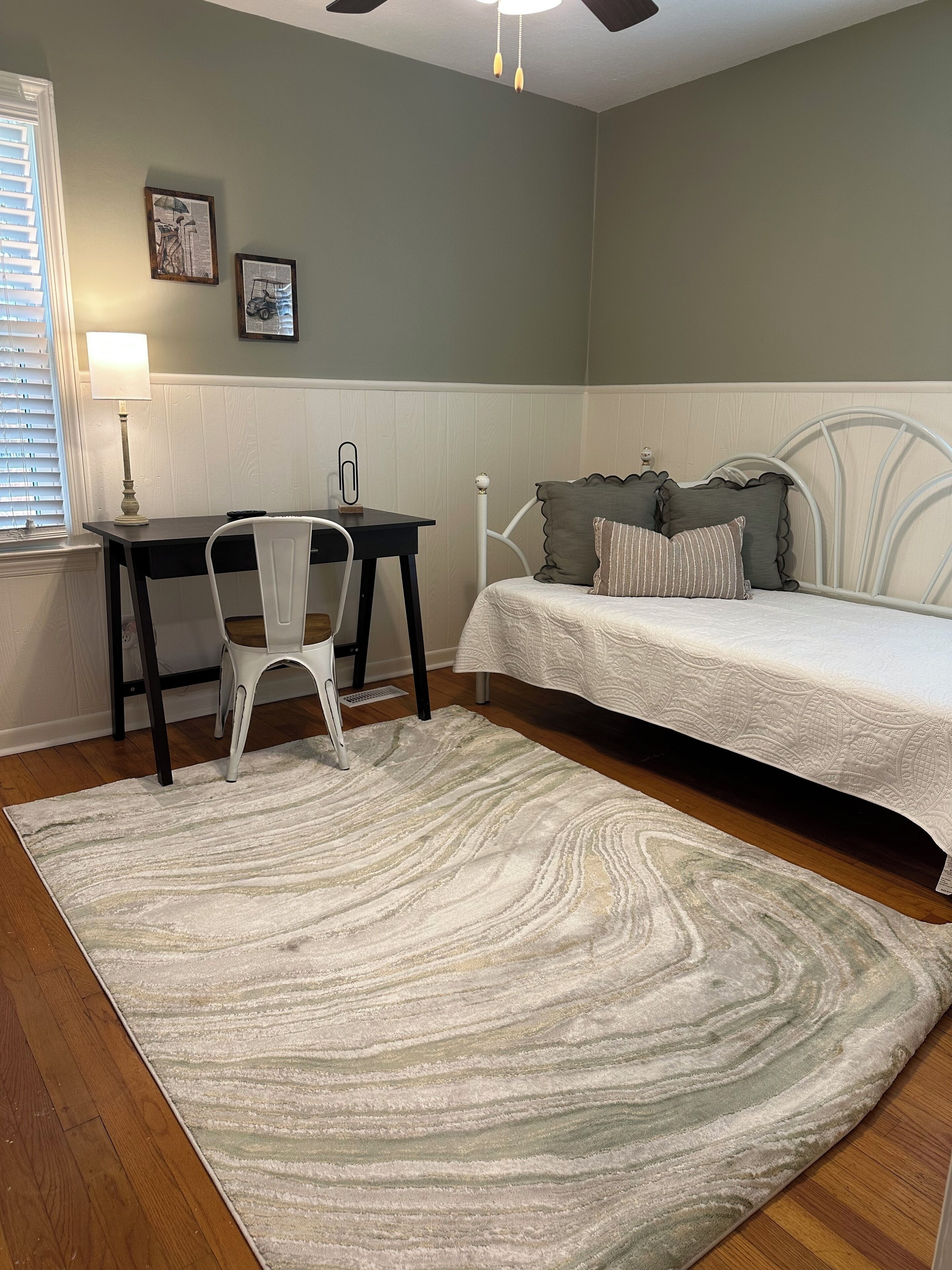 Ein Schlafzimmer mit Bett, Schreibtisch, Stuhl und Teppich.