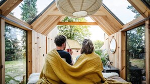 A cozy wooden room with a bed, a table, and a hanging light fixture.