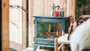 A cozy wooden room with a fireplace, a round mirror, and a table with chairs.