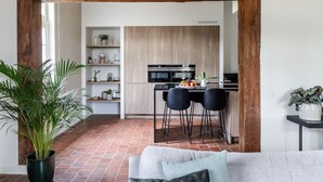 A modern kitchen with a central island, black bar stools, and a dining table.