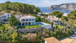 Experience a villa with a spacious outdoor pool surrounded by lush greenery and a scenic sea view.