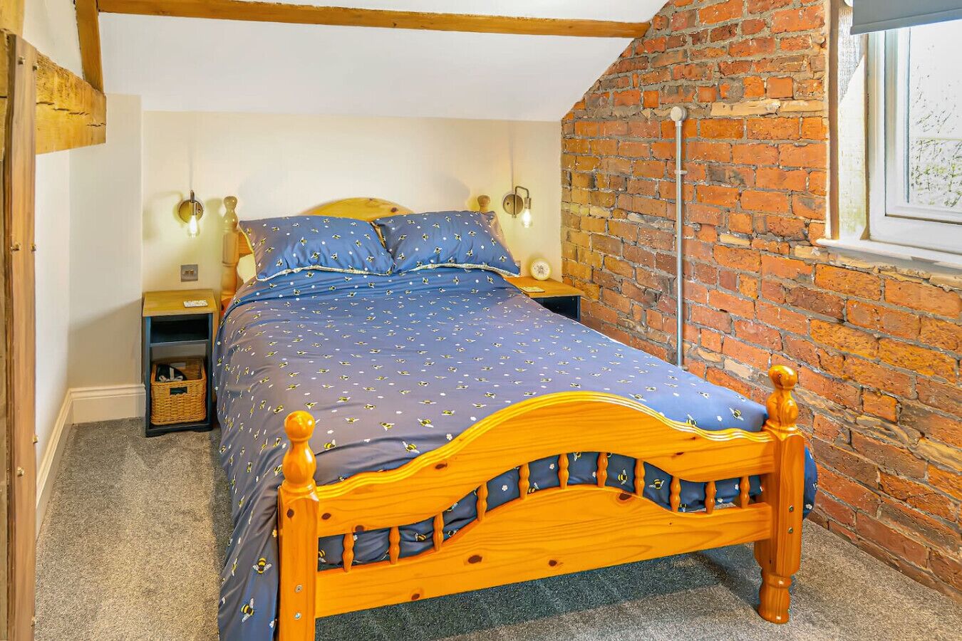 Une chambre avec un lit en bois, un mur en briques et une fenêtre.