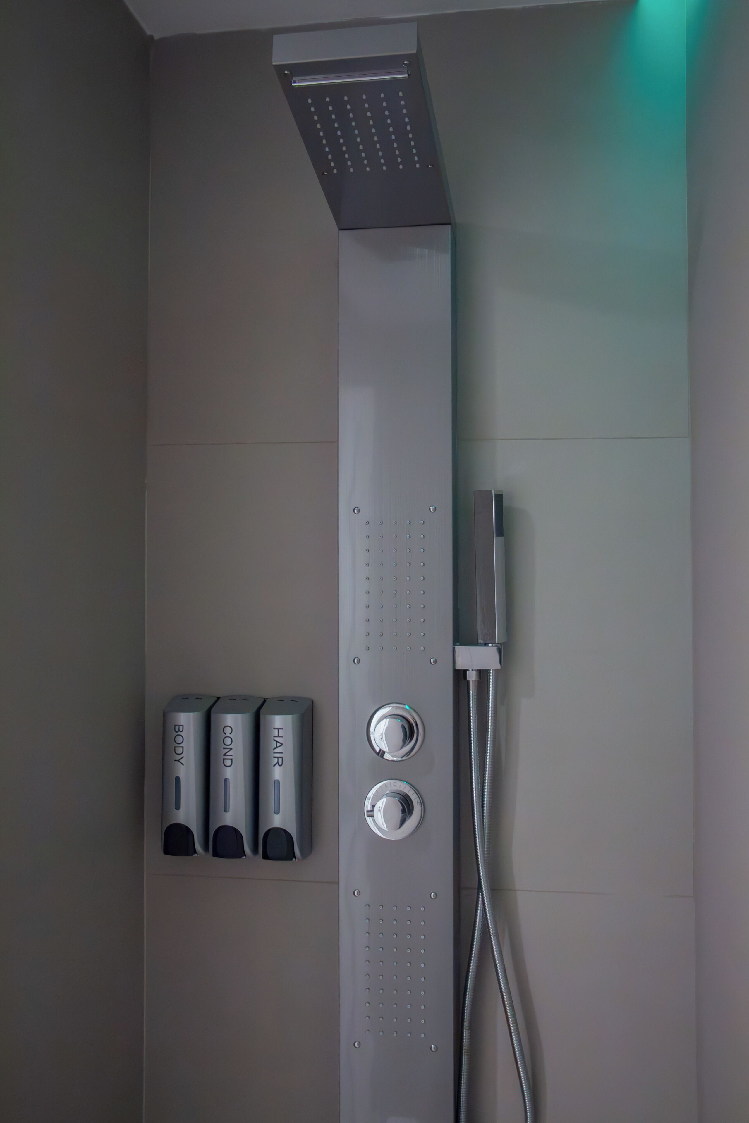 A modern shower with a control panel, a handheld showerhead, and a handheld massager.