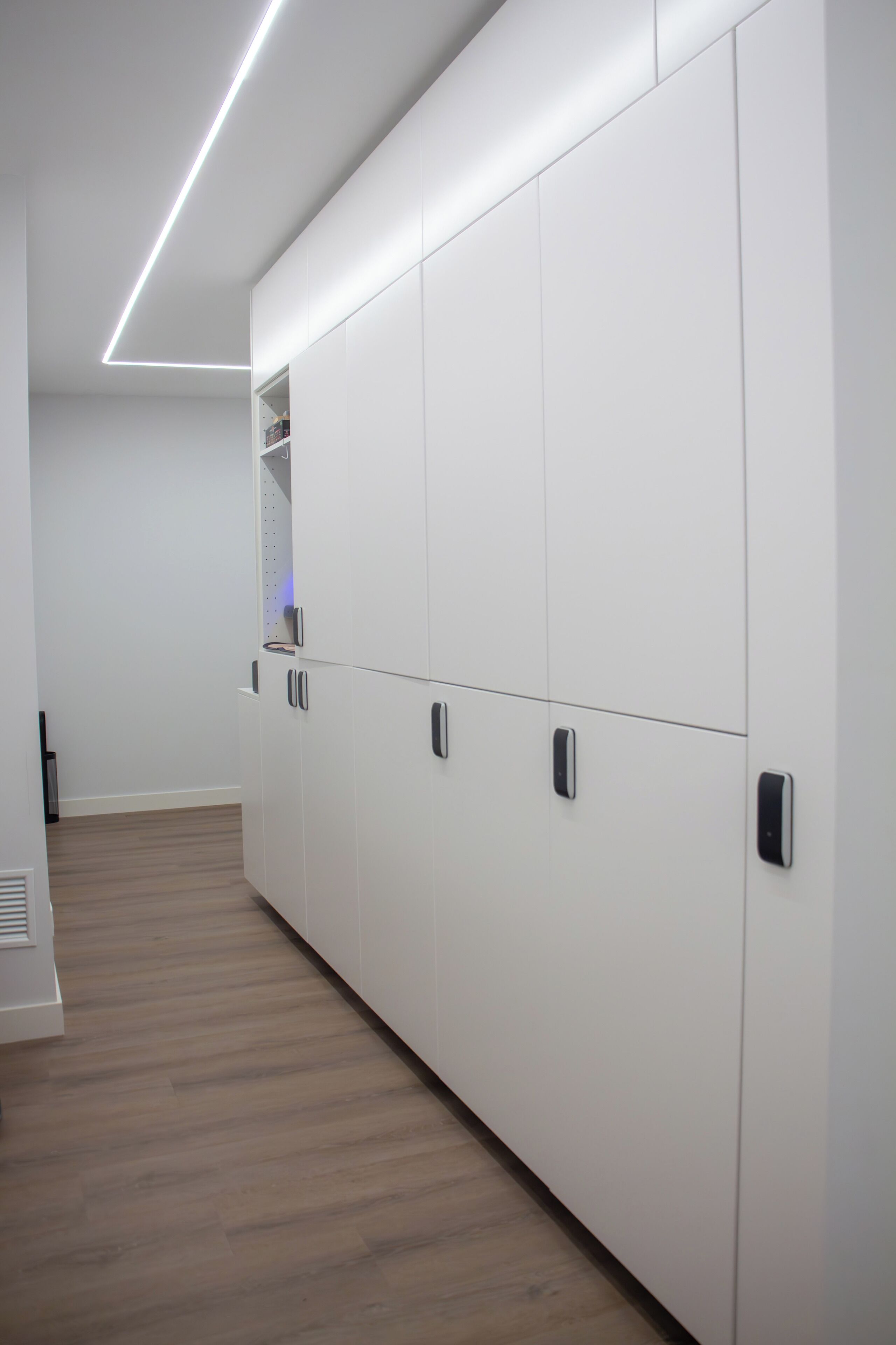 Un couloir avec des armoires blanches et un plancher en bois.