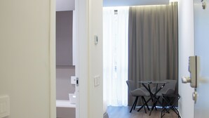 Un intérieur moderne avec un coin repas comprenant une table et des chaises, une porte visible donnant sur une autre pièce et un plancher de couleur claire.