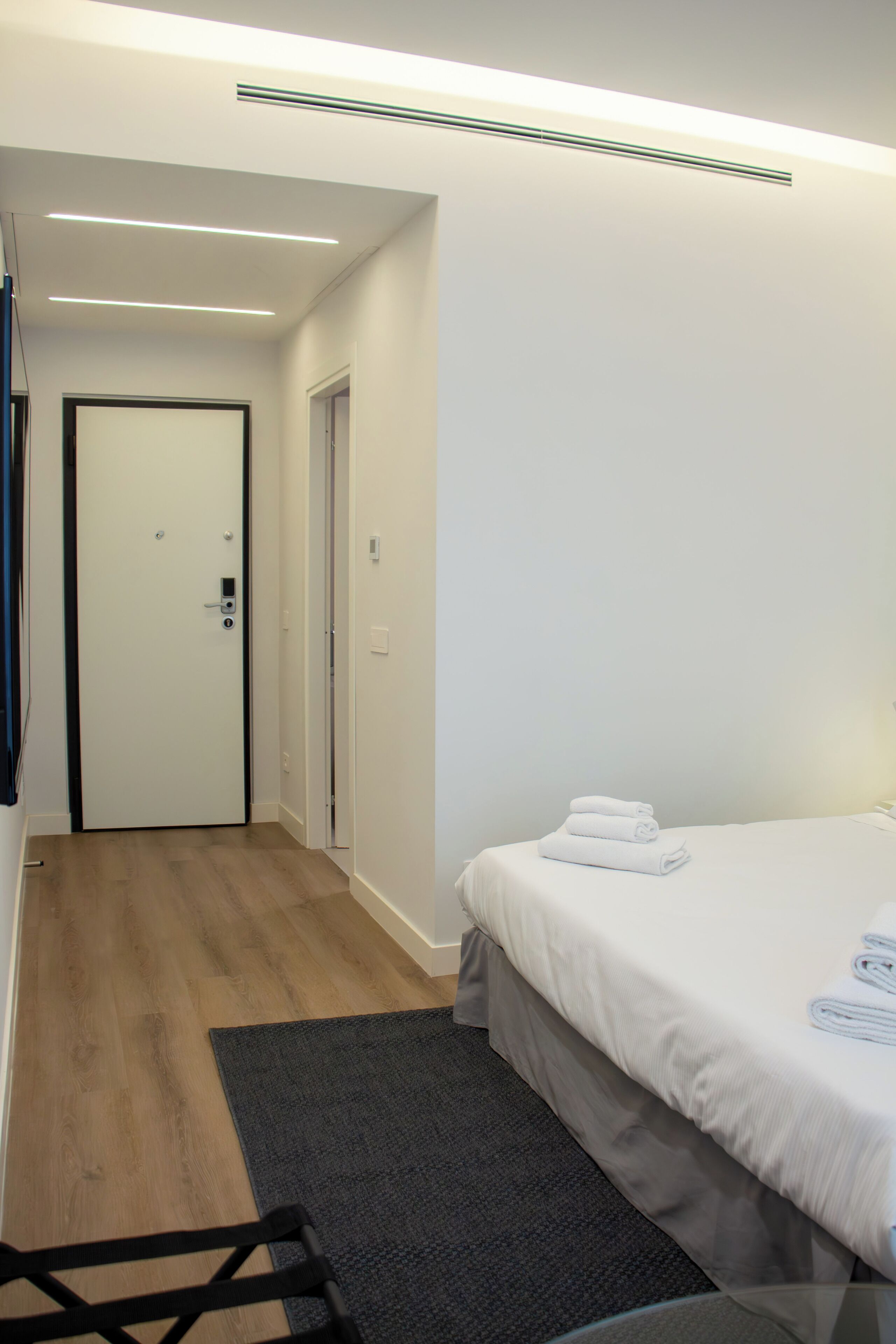 Et hotelværelse med en seng, et skrivebord og en dør.