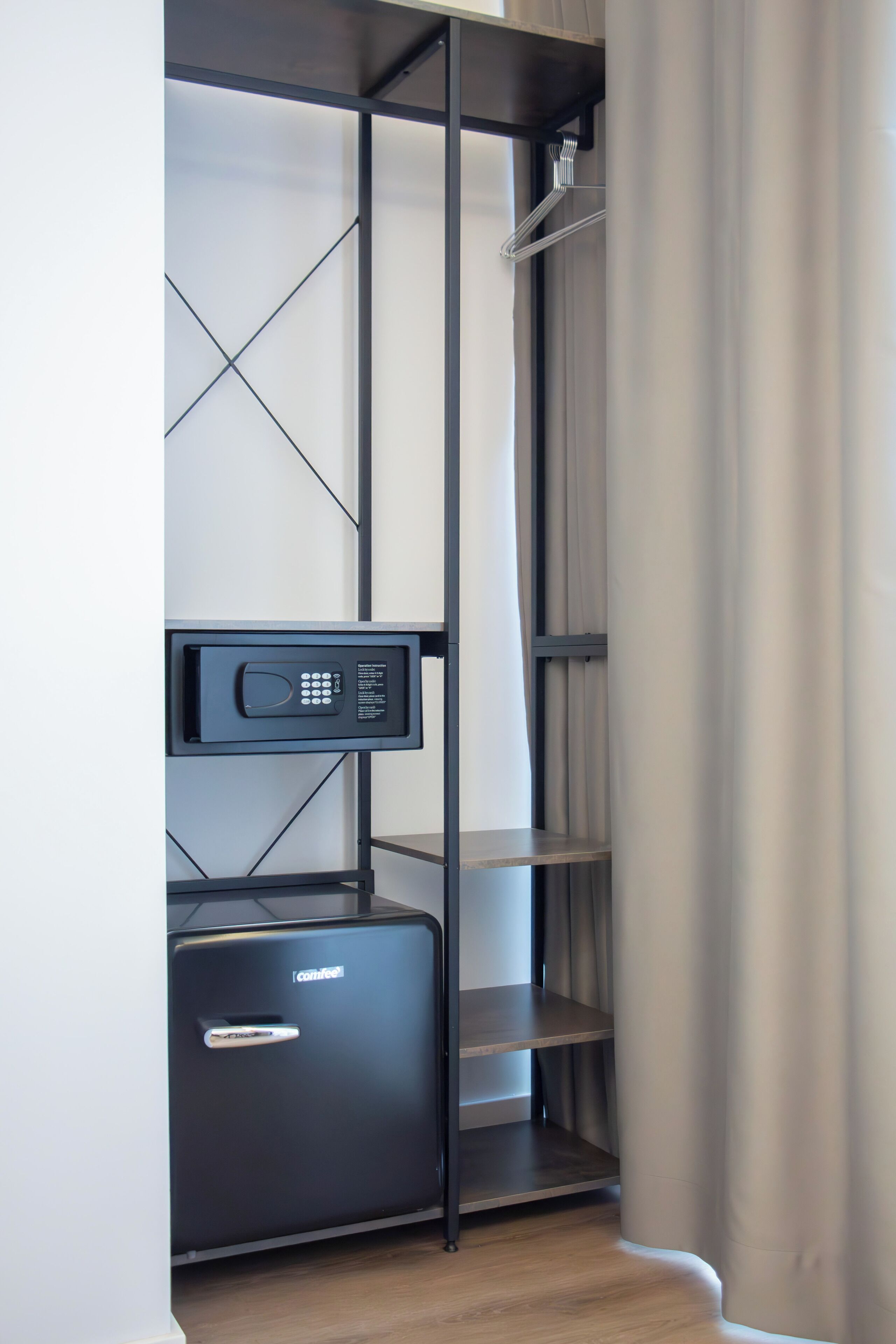 A modern closet with a built-in safe, shelves, and a hanging rod.
