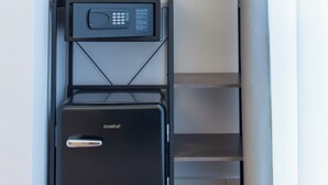 Un meuble de rangement compact doté d’un micro-ondes et d’un petit réfrigérateur, avec une structure en métal et des étagères ouvertes.