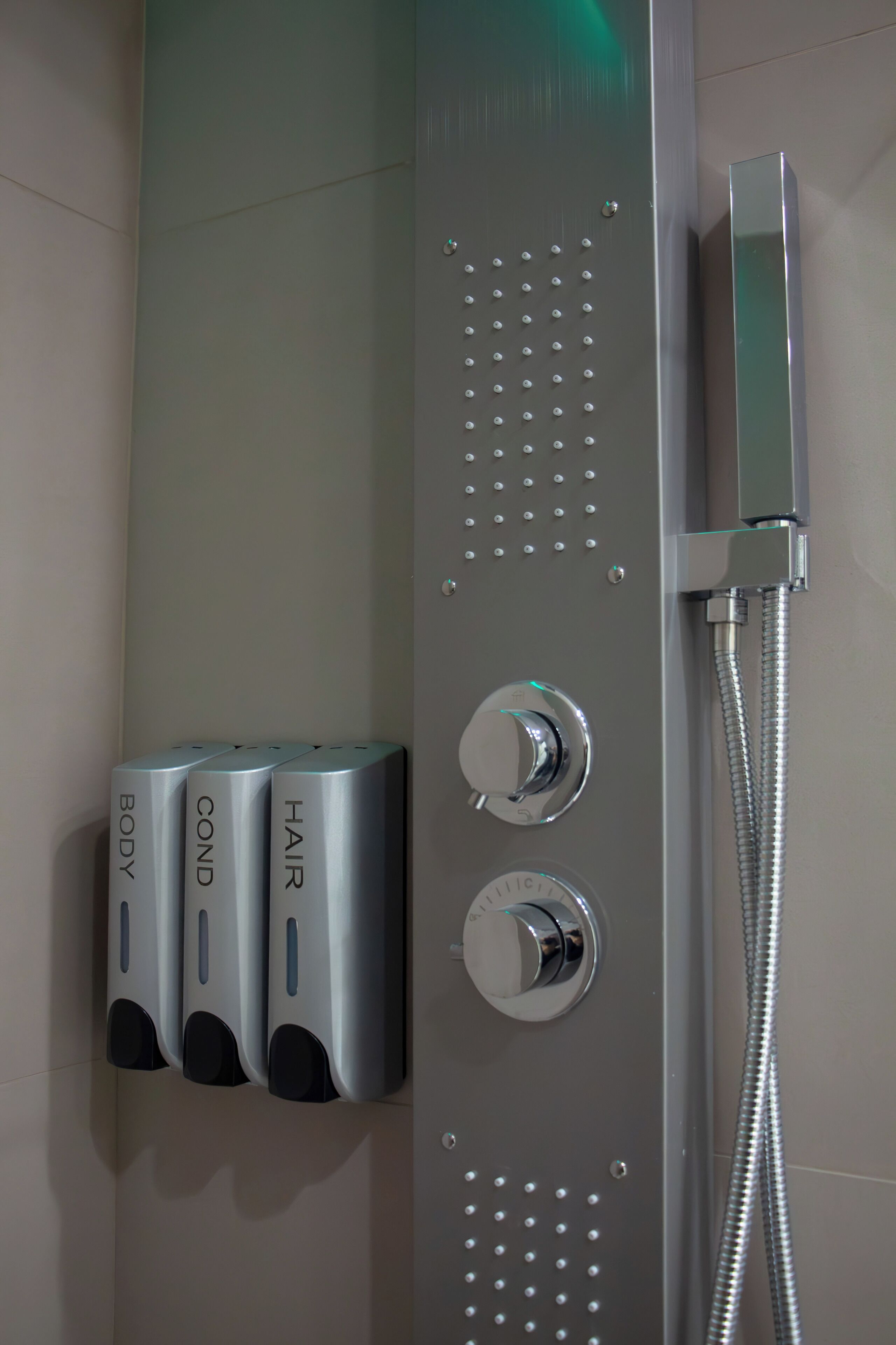 A modern shower control panel with multiple spray heads and a handheld showerhead.