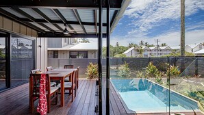 Une terrasse extérieure moderne avec une piscine, des meubles en bois et une structure en verre.