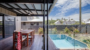 Une terrasse extérieure moderne avec une piscine, des meubles en bois et une structure en verre.