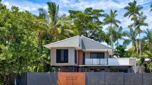 Une maison moderne à deux étages, dotée d’un toit plat, de grandes fenêtres et d’un balcon.