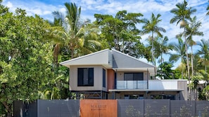 Une maison moderne à deux étages, dotée d’un toit plat, de grandes fenêtres et d’un balcon.