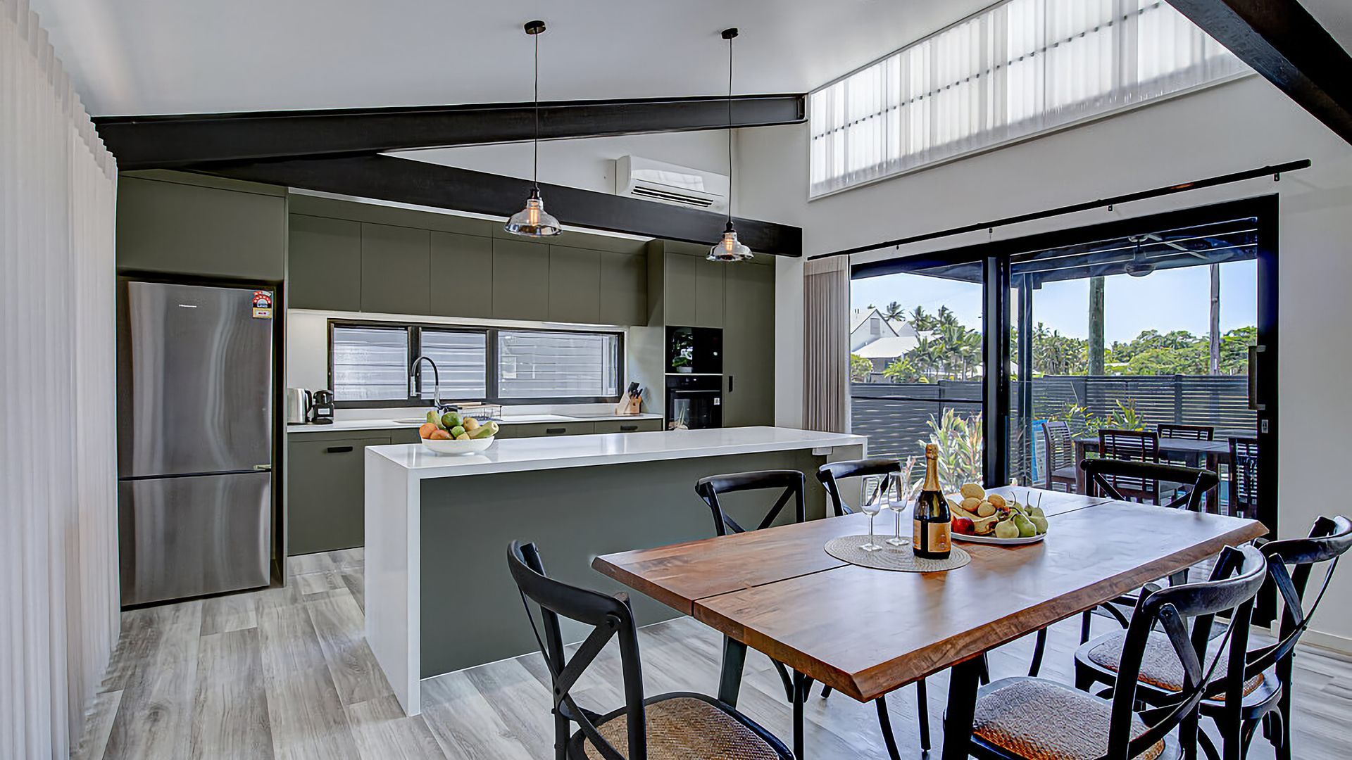 A modern kitchen with a central island, dining table, and chairs.