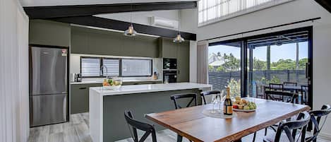 A modern kitchen with a central island, dining table, and chairs.