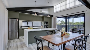 Een moderne keuken met een centraal eiland, een eettafel en stoelen.