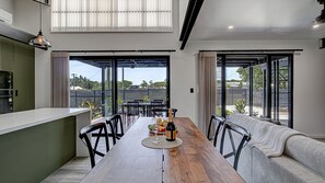 Een moderne eetruimte met een houten tafel, stoelen en een bank.