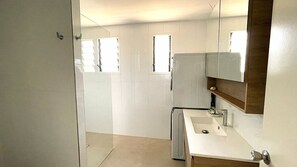A bathroom with a sink, mirror, and a shower area.