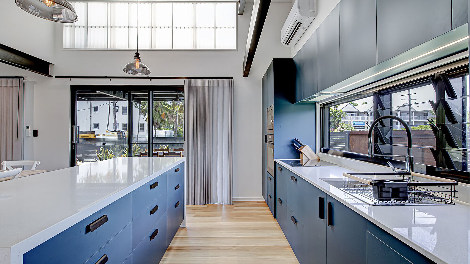 A modern kitchen with a central island, a window with a view, and a built-in oven.