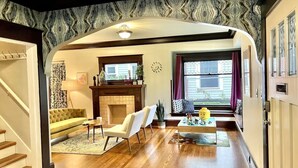 A living room with a fireplace, a sofa, a coffee table, and a window with curtains.