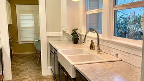 A kitchen with dark cabinets, a white countertop, a sink, and pendant lights.