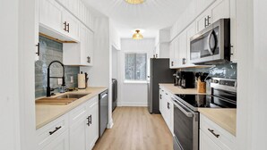 A narrow kitchen with white cabinets, a wooden countertop, a stainless steel refrigerator, and a microwave. - Coastal 4BR Oasis: Close to the Beach & Coligny Plaza (Hilton Head Island)