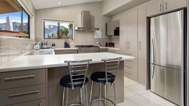 Una cocina moderna con una isla grande, electrodomésticos de acero inoxidable y vistas a la montaña a través del ventanal.