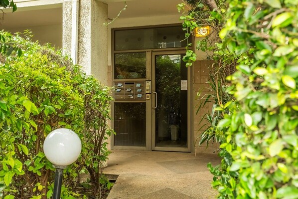 A hotel entrance with a glass door, a keypad for room access, and a small outdoor light fixture.