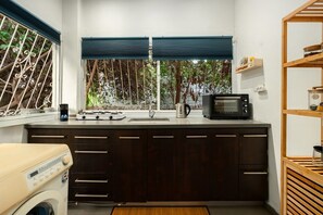 A compact kitchen with a built-in washing machine, a microwave, and a sink. - Cozy Old North Stay • Steps from Yarkon Park (Tel Aviv)